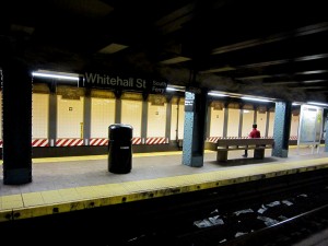 The standard layout of a subway station: A map, a bench, a sign, a trashcan and lots of trash on the tracks.